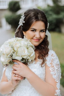 Portre. Elbise ve peçeli esmer bir gelin, diyademiyle buketle poz veriyor. Gümüş mücevherler. Güzel makyaj ve saç. Sonbahar düğünü. kutlama