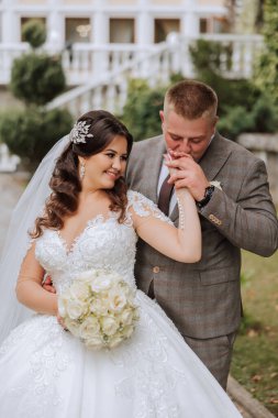 Damat gelinin elini öpüyor. Birbirine aşık bir çiftin düğün fotoğrafı. Genç ve yakışıklı bir adam karısının elini altın bir yüzükle öpüyor..