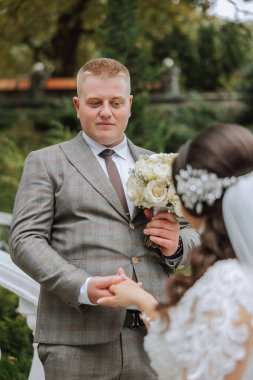 Damat gelinin elini öpüyor. Birbirine aşık bir çiftin düğün fotoğrafı. Genç ve yakışıklı bir adam karısının elini altın bir yüzükle öpüyor..