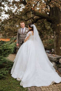 Sonbahar parkında yürüyüş yapan düğün çifti. Güzel beyaz elbiseli gelin. Aşk ve ilişki kavramı. Doğada damat ve gelin