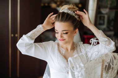 Yatak odasında beyaz bornozlu inanılmaz güzel bir kızın portresi. Gelin düğün töreninden önce sabah poz veriyor..