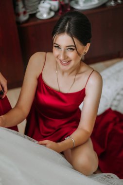 Odada aynı kırmızı elbiseli güzel kızlar var. Kırmızı elbiseli bir arkadaş gelinin düğün törenine hazırlanmasına yardım eder.