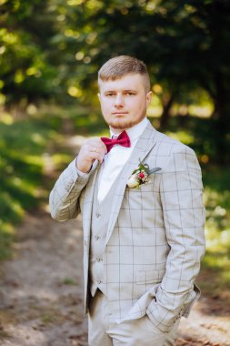 Bir sonbahar gününde zarif bir takım elbiseyle yakışıklı bir damadın portresi. Açık hava fotoğrafı. Takım elbiseli yakışıklı bir adam..