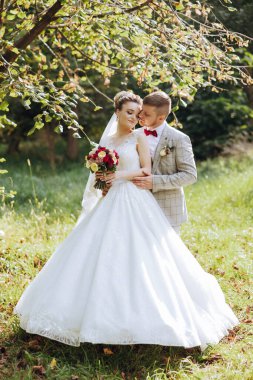 Genç bir gelin ve damat sonbahar güneşinin ışınlarında şefkatle kucaklaşır. Şefkatli ve güzel genç kız gelin. Bir adam sevgilisini öper. Güzel bir bahçenin arka planında