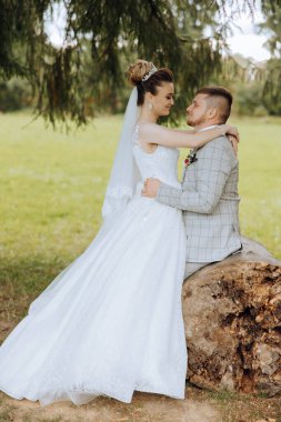 Genç bir gelin ve damat sonbahar güneşinin ışınlarında şefkatle kucaklaşır. Şefkatli ve güzel genç kız gelin. Bir adam sevgilisini öper. Güzel bir bahçenin arka planında