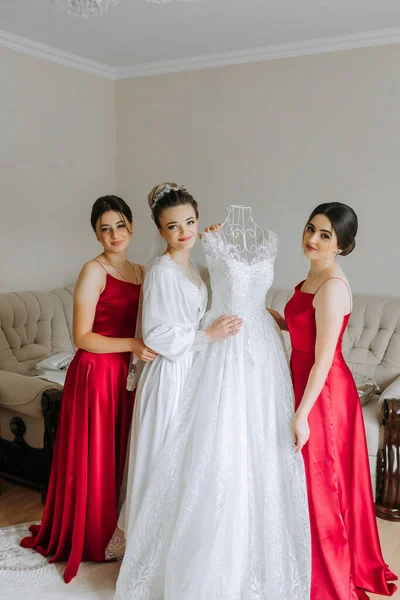 Portrait of the bride with her friends. Elegant and stylish bride with her friends in matching dresses in the room in the morning. Many beautiful girls in one photo.
