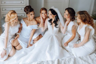 Gelin ve arkadaşlarının portresi. Şık ve şık bir gelin ve arkadaşları sabahları aynı elbiselerle odada. Bir fotoğrafta bir sürü güzel kız var..