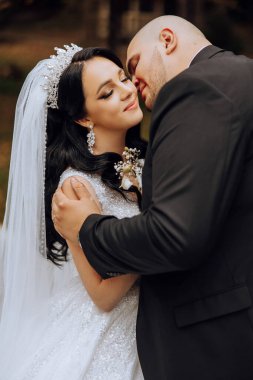 Genç bir gelin ve damat sonbahar güneşinin ışınlarında şefkatle kucaklaşır. Şefkatli ve güzel genç kız gelin. Bir adam sevgilisini öper. Güzel bir bahçenin arka planında