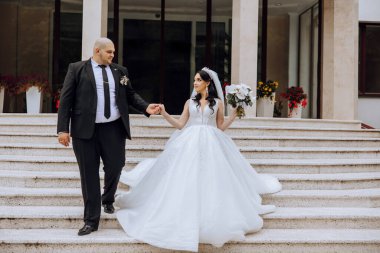 Bir düğün çifti bir sonbahar günü doğada yürüyor. Mutlu genç gelin ve zarif damat el ele tutuşuyor. Yeni evlilerin düğün gününde şık bir çift..