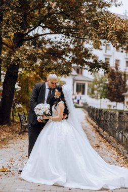 Genç bir gelin ve damat sonbahar güneşinin ışınlarında şefkatle kucaklaşır. Şefkatli ve güzel genç kız gelin. Bir adam sevgilisini öper. Güzel bir bahçenin arka planında