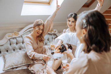 Sabahları güzel bir otelde nedimelerin şampanya içtiği bir fotoğraf. Düğünden önce şampanya içen güzel bir gelin ve eşleşen elbiseli arkadaşlarının fotoğrafı..