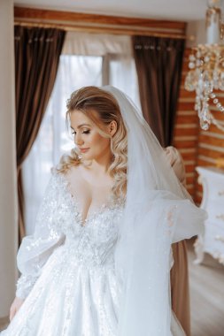 Evdeki düğün töreninden önce küpe takan genç ve güzel bir gelin. Beyaz gelinlikli bir gelin, sabahları odasına küpe takar..