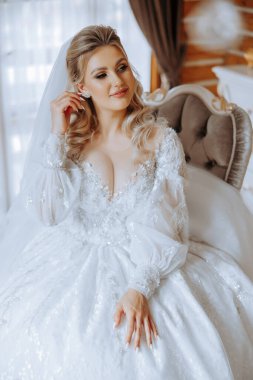 Evdeki düğün töreninden önce küpe takan genç ve güzel bir gelin. Beyaz gelinlikli bir gelin, sabahları odasına küpe takar..