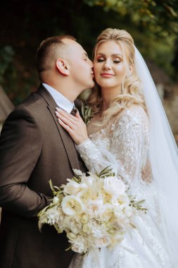 Genç bir gelin ve damat sonbahar güneşinin ışınlarında şefkatle kucaklaşır. Şefkatli ve güzel genç kız gelin. Bir adam sevgilisini öper. Güzel bir bahçenin arka planında