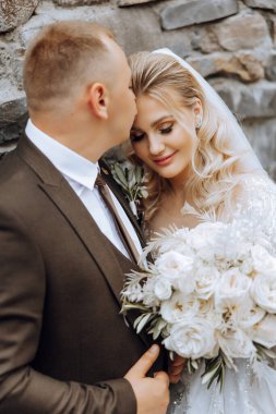 Genç bir gelin ve damat sonbahar güneşinin ışınlarında şefkatle kucaklaşır. Şefkatli ve güzel genç kız gelin. Bir adam sevgilisini öper. Güzel bir bahçenin arka planında