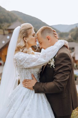 Şirin ve şık yeni evliler güzel bir bahçede sonbahar doğasının arka planına sarılıp gülümsüyorlar. İnanılmaz güzel genç bir gelin sevgilisini öper.