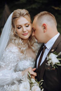 Genç bir gelin ve damat sonbahar güneşinin ışınlarında şefkatle kucaklaşır. Şefkatli ve güzel genç kız gelin. Bir adam sevgilisini öper. Güzel bir bahçenin arka planında