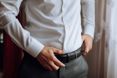 Beyaz adamın kemerini taktığı yakın plan çekimler. Şık bir adam yakın plan deri kemer takıyor. Moda.