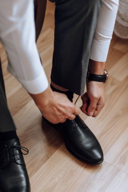 Bir adam otel odasındaki bir kanepede otururken ayakkabılarını giyiyor. Genç bir girişimci bir iş gezisine gitmeye hazırlanıyor. İşadamı sabah erkenden yatak odasına gitmeye hazırlanıyor.