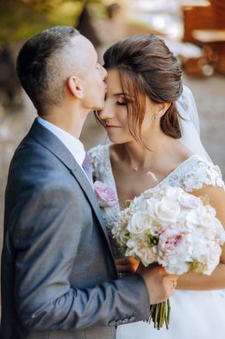 Genç bir gelin ve damat sonbahar güneşinin ışınlarında şefkatle kucaklaşır. Şefkatli ve güzel genç kız gelin. Bir adam sevgilisini öper. Güzel bir bahçenin arka planında