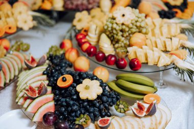 Meyve ve böğürtlen dolu bir ziyafet masası, bir sürü tatlı. Muz, üzüm, ananas. Tatil için meyve kompozisyonları.