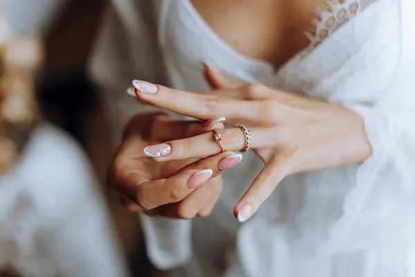 Close-up of an elegant diamond ring on a woman\'s finger with a modern manicure, sunlight. Love and wedding concept. Soft and selective focus.