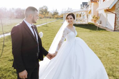 Bir düğün çifti bir sonbahar günü doğada yürüyor. Mutlu genç gelin ve zarif damat el ele tutuşuyor. Yeni evlilerin düğün gününde şık bir çift..