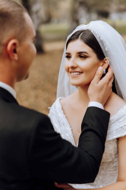 Sonbahar parkında yürüyüş yapan düğün çifti. Güzel beyaz elbiseli gelin. Aşk ve ilişki kavramı. Doğada damat ve gelin