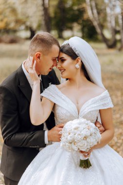 Genç bir gelin ve damat sonbahar güneşinin ışınlarında şefkatle kucaklaşır. Şefkatli ve güzel genç kız gelin. Bir adam sevgilisini öper. Güzel bir bahçenin arka planında