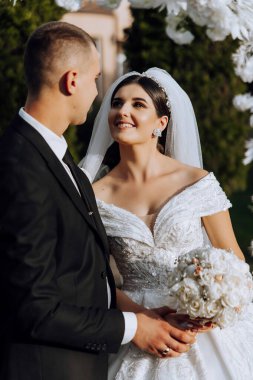 Genç bir gelin ve damat sonbahar güneşinin ışınlarında şefkatle kucaklaşır. Şefkatli ve güzel genç kız gelin. Bir adam sevgilisini öper. Güzel bir bahçenin arka planında