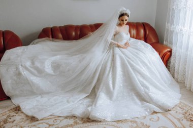 İnanılmaz güzel bir gelin yatak odasında bir yatakta oturur. Gelin sabahı. Parlak bir odadaki bir yatakta oturan güzel elbiseli muhteşem bir gelin. .