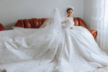 İnanılmaz güzel bir gelin yatak odasında bir yatakta oturur. Gelin sabahı. Parlak bir odadaki bir yatakta oturan güzel elbiseli muhteşem bir gelin. .