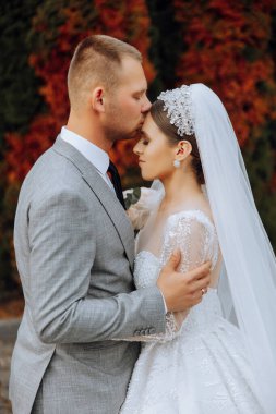Genç bir gelin ve damat sonbahar güneşinin ışınlarında şefkatle kucaklaşır. Şefkatli ve güzel genç kız gelin. Bir adam sevgilisini öper. Güzel bir bahçenin arka planında