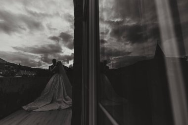 Yakışıklı bir damat, sevgilisini güzel bir yerde kucaklar. Gelin ve damadın aynasındaki yansıma. Geniş biçimli fotoğraf.