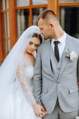 Güzel ve şık yeni evliler güzel bir bahçede sonbahar doğasının arka planına karşı sarılıp gülümsüyorlar. İnanılmaz güzel genç bir gelin, sevgili damadının omzuna yaslandı.