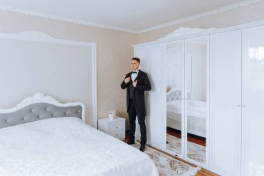 Düğünden önce ceketinin düğmelerini ilikleyen genç bir adam. Takım elbiseli bir adamın yakın çekimi. İş adamı takım elbise giyer. Bir adam ceketinin düğmelerini bağlar..