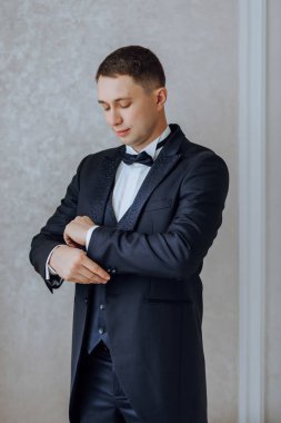 Düğünden önce ceketinin düğmelerini ilikleyen genç bir adam. Takım elbiseli bir adamın yakın çekimi. İş adamı takım elbise giyer. Bir adam ceketinin düğmelerini bağlar..