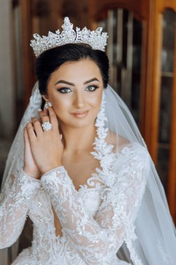 Evdeki düğün töreninden önce küpe takan genç ve güzel bir gelin. Beyaz gelinlikli bir gelin, sabahları odasına küpe takar..