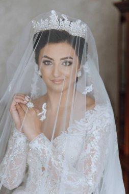 Beyaz gelinlik içinde duvak tutan genç bir gelin otel odasında esmer gelin portresi, düğünden önceki sabah..