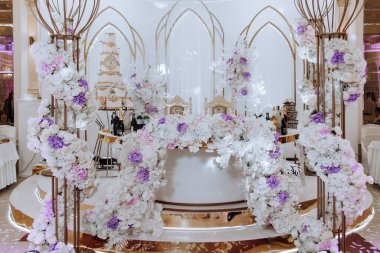 Tatil için bir restoranda masa hazırlıyorum. Şölende yeni evliler için düğün dekoru. Çiçekler ve mumlar, boho tarzı. Gelin ve misafirler için yemek servisi..