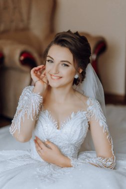 Evdeki düğün töreninden önce küpe takan genç ve güzel bir gelin. Beyaz gelinlikli bir gelin, sabahları odasına küpe takar..