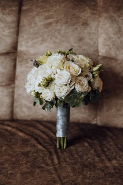 Düğün buketi. Taze kesilmiş güller, yeşil tohum başları ve yapraklar. Yeşil saplar, beyaz kurdele ve altın alyanslar. Düğün buketi konsepti.