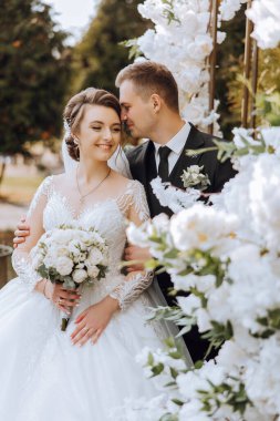 Genç bir gelin ve damat sonbahar güneşinin ışınlarında şefkatle kucaklaşır. Şefkatli ve güzel genç kız gelin. Bir adam sevgilisini öper. Güzel bir bahçenin arka planında