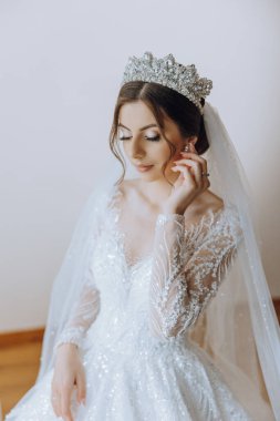 Evdeki düğün töreninden önce küpe takan genç ve güzel bir gelin. Beyaz gelinlikli bir gelin, sabahları odasına küpe takar..