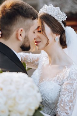 Genç bir gelin ve damat sonbahar güneşinin ışınlarında şefkatle kucaklaşır. Şefkatli ve güzel genç kız gelin. Bir adam sevgilisini öper. Güzel bir bahçenin arka planında