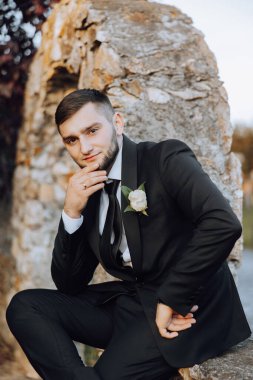 Bir sonbahar gününde zarif bir takım elbiseyle yakışıklı bir damadın portresi. Açık hava fotoğrafı. Takım elbiseli yakışıklı bir adam..