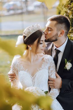 Genç bir gelin ve damat sonbahar güneşinin ışınlarında şefkatle kucaklaşır. Şefkatli ve güzel genç kız gelin. Bir adam sevgilisini öper. Güzel bir bahçenin arka planında