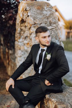 Bir sonbahar gününde zarif bir takım elbiseyle yakışıklı bir damadın portresi. Açık hava fotoğrafı. Takım elbiseli yakışıklı bir adam..