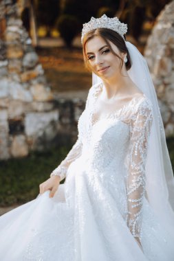 Düğün portresi. Dantelli, omuzları açık, esmer bir gelin doğada poz veriyor. Güzel saç ve makyaj. Sonbahar. Gün ışığı. kutlama.