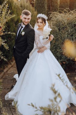 Sonbahar parkında yürüyüş yapan düğün çifti. Güzel beyaz elbiseli gelin. Aşk ve ilişki kavramı. Doğada damat ve gelin